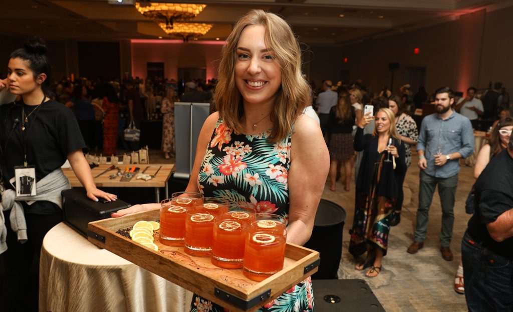 woman at event with tray of cocktails