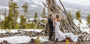 wedding on mountain in front of pile of logs
