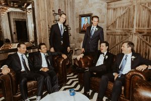 groom and groomsmen sitting on leather couches