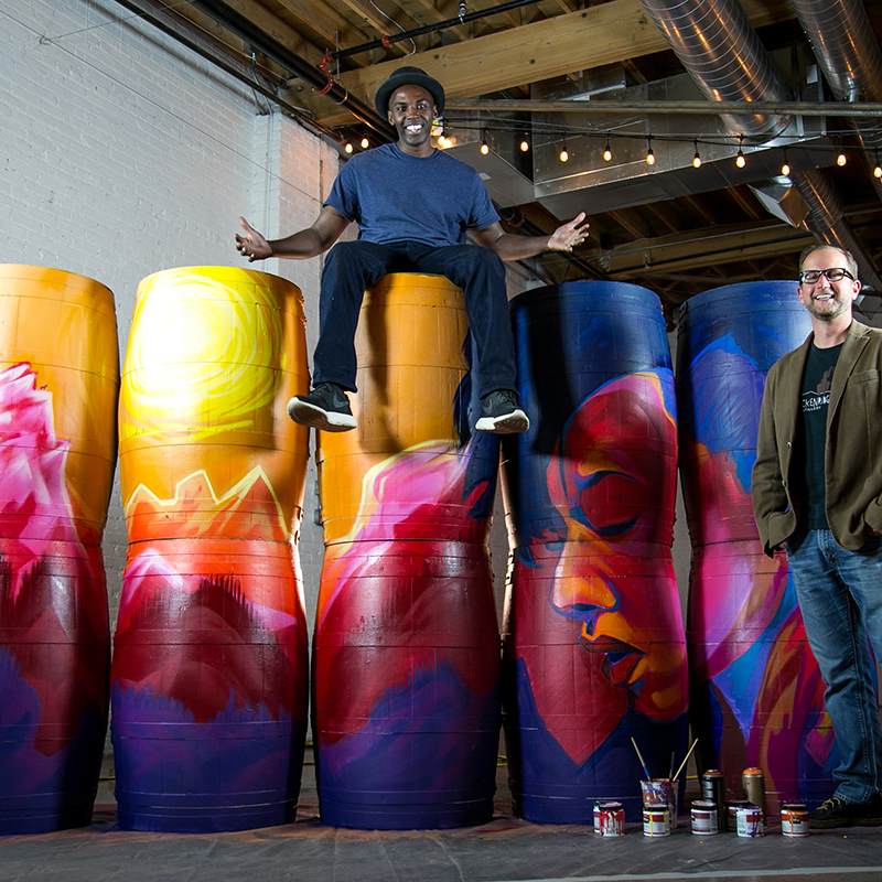 artist on top of painted barrels
