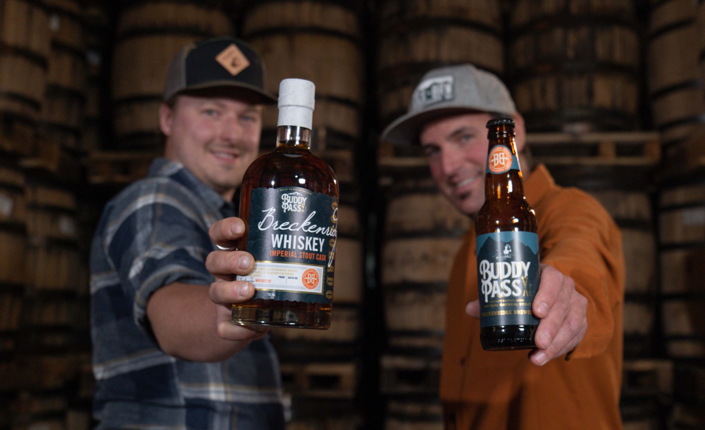 two men holding Breckenridge Imperial Stout Cask bottle and Buddy Pass Imperial Oatmeal Stout drinks
